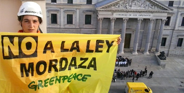 Activista de Greenpeace sujeta un cartel contra la Ley Mordaza frente al Congreso - Foto: Greenpeace