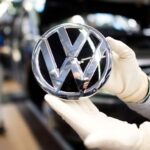 Trabajador de Volkswagen muestra el logo de la automotriz alemana