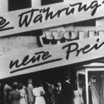 Clientes se agolpan frente a un negocio que después de la reforma monetaria en Alemania. En la fachada se lee "¡Nueva moneda... nuevos precios!". En 1948 se introdujo el marco alemán