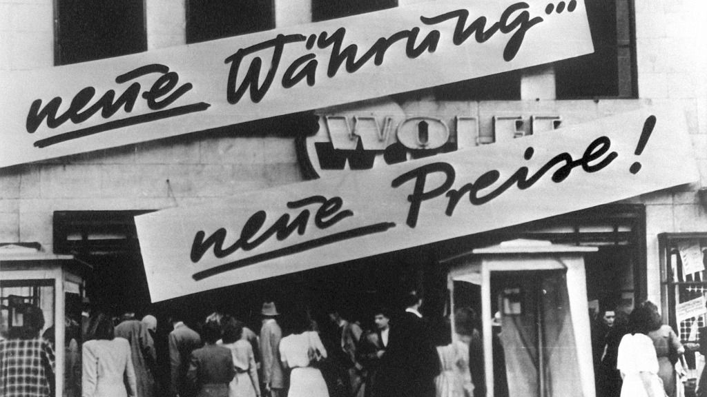 Clientes se agolpan frente a un negocio que después de la reforma monetaria en Alemania. En la fachada se lee "¡Nueva moneda... nuevos precios!". En 1948 se introdujo el marco alemán