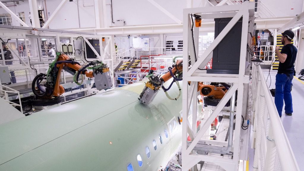 Un empleado de Airbus observa el trabajo de dos robots en el fuselaje de un modelo A320 en la planta de la empresa en Finkenwerder, al sur de Hamburgo