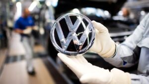 Trabajador de Volkswagen muestra el logo de la automotriz alemana