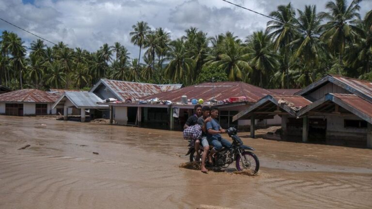 Un hombre conduce su motocicleta a través del lodo tras las fuertes lluvias que provocaron inundaciones en la provincia de Bengkulu, en la isla indonesia de Sumatra