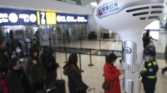 Personal del Aeropuerto Internacional de Tianhe en Wuhan (China) toma la temperatura a pasajeros