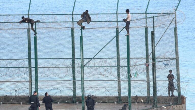 En la imagen, tres de un total de 153 migrantes, entran en Ceuta saltando su doble valla en la primera incursión en grupo en un año.