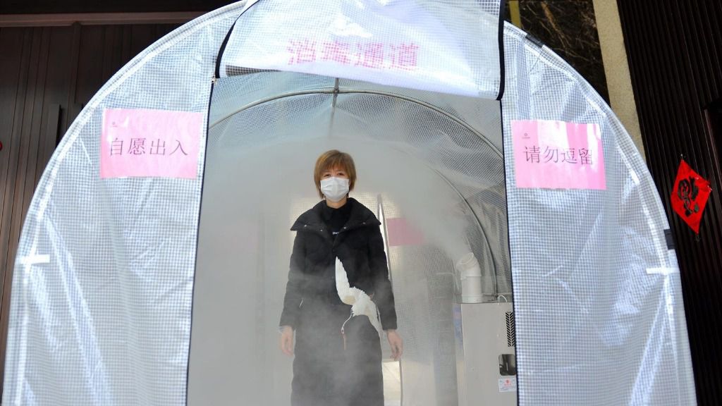 Una mujer camina a través de un canal de desinfección situado en la ciudad de Hefei, en el oeste de China