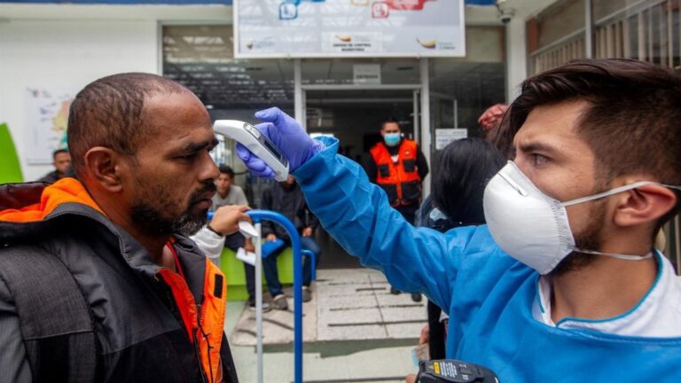 Médico ecuatoriano toma la temperatura a un hombre en la frontera con Colombia.