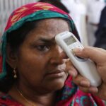 Funcionarios de las autoridades sanitarias de Bangladesh toma la temperatura a una mujer en Daca, la capital del país
