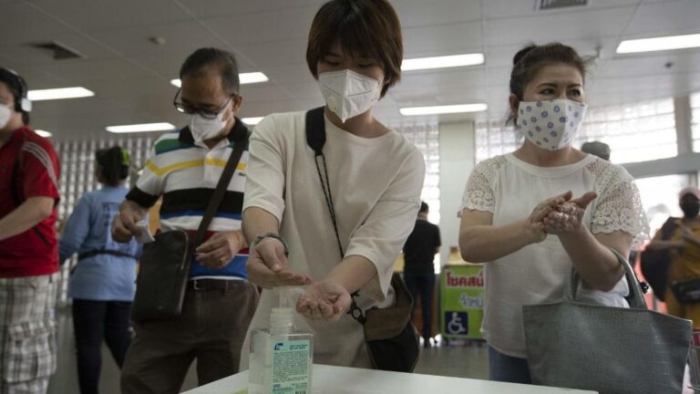 Un grupo de personas se desinfectan las manos con gel antes de entrar a un supermercado en Bangkok, Tailandia