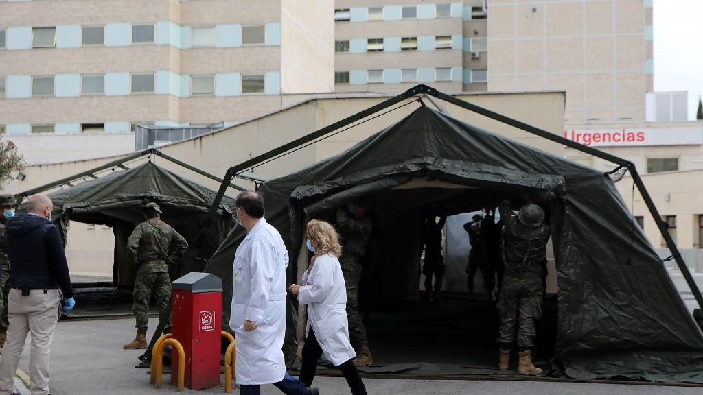 Personal sanitario pasa junto a militares en las inmediaciones del Hospital Gregorio Marañón