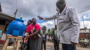 Un médico toma la temperatura mientras una mujer se lava las manos en Nairobi