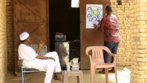 Sudaneses frente a un cartel informativo sobre las medidas de protección ante la pandemia de coronavirus