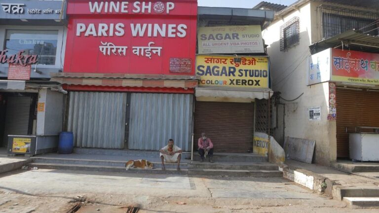 Dos ciudadanos sentados a las puertas de una tienda de vinos en Bombay