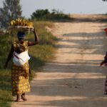 Dos mujeres caminan por un camino de Kigali, capital de Ruanda, portando sendas cestas de plátanos