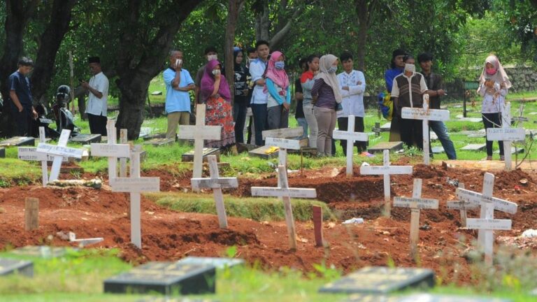 Personas con mascarilla por el coronavirus en un cementerio de Yakarta