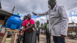 Un médico toma la temperatura mientras una mujer se lava las manos en Nairobi