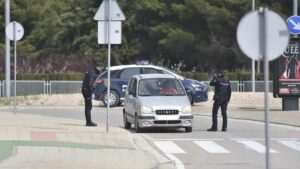 Dos policias nacionales paran a un coche estacionado durante el cuarto día laboral en el estado de alarma en el país por el coronavirus