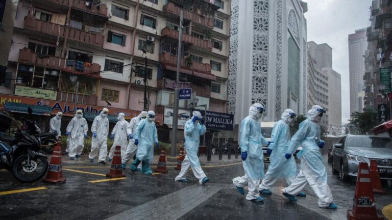 Trabajadores del Ministerio de Sanidad saliendo de un edifcio de Johannesburgo tras hacer pruebas de coronavirus a los vecinos