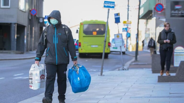 Un hombre camina por las calles de Oslo, Noruega, cubriéndose la boca con una mascarilla