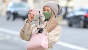 Una mujer con mascarilla haciendo una foto con su smartphone en Londres