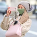 Una mujer con mascarilla haciendo una foto con su smartphone en Londres