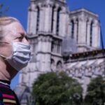 Una mujer con mascarilla pasa por delante de Notre Dame coronavirus francia