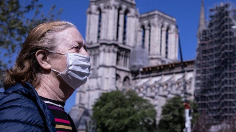 Una mujer con mascarilla pasa por delante de Notre Dame coronavirus francia