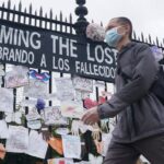 Un hombre pasa ante una verja en Nueva York con mensajes en memoria de los fallecidos por la pandemia del coronavirus