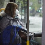 Una mujer con mascarilla en un autobús urbano