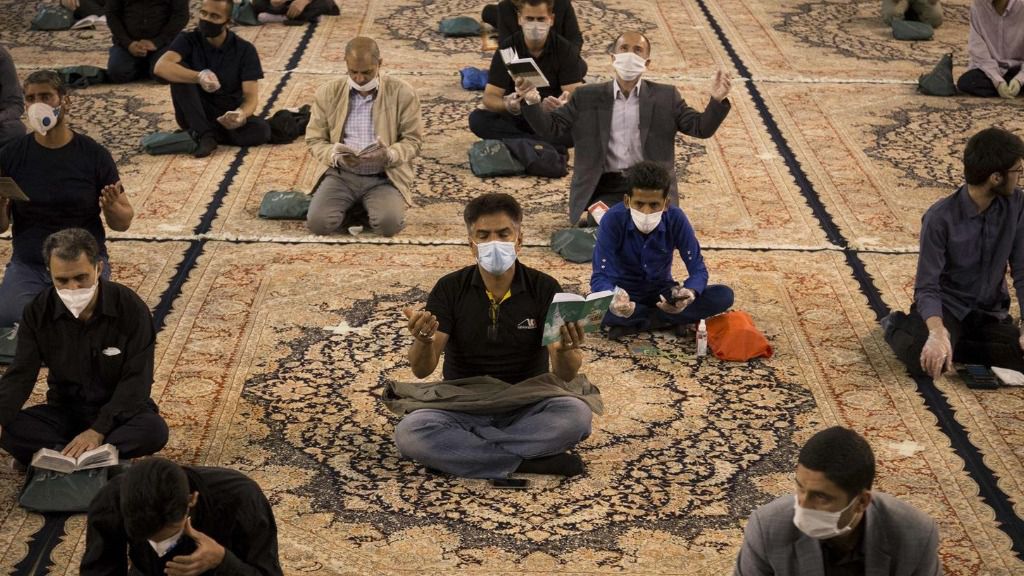 Hombres rezando con mascarilla en una mezquita en Teherán