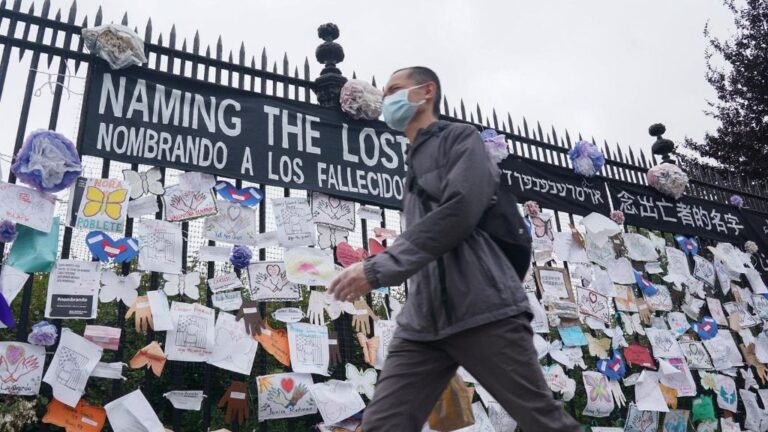 Un hombre pasa ante una verja en Nueva York con mensajes en memoria de los fallecidos por la pandemia del coronavirus