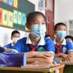 Niños chinos acuden a clase en Pekín china coronavirus