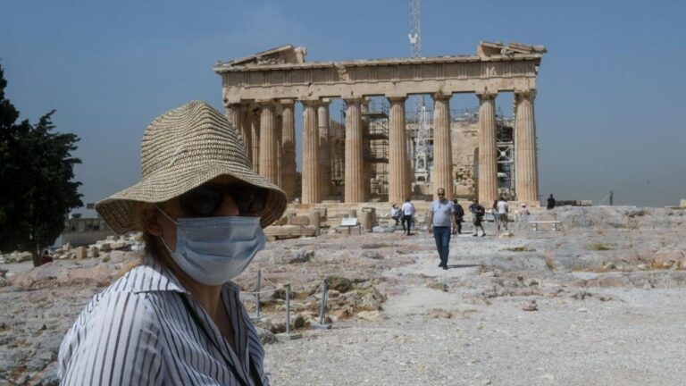 Una mujer con mascarilla frente al Partenón de Atenas