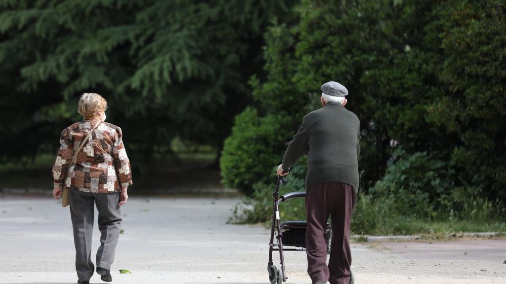 Una mujer y un hombre de edad avanzada pasen por la calle