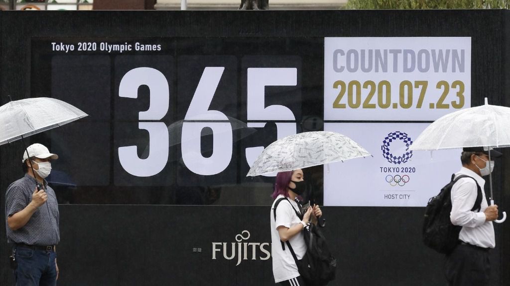 Personas con mascarilla en un paseo que muestra la cuenta atrás para los Juegos Olímpicos de Tokio
