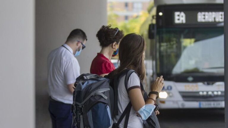 Varias personas en la parada del bus exprés hacia el aeropuerto.