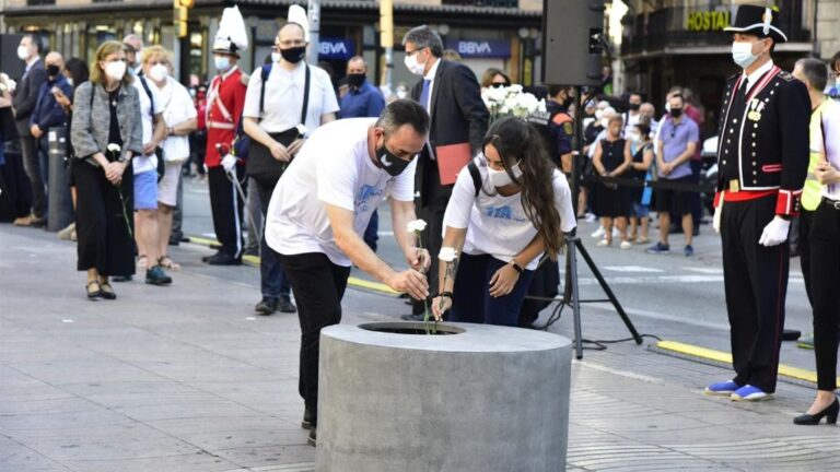 Asistentes dejan rosas blancas y carteles en recuerdo a las 16 personas fallecidas el 17 de agosto de 2017 y a los más de 150 heridos en los atentados de Barcelona y Cambrils durante el homenaje y minuto de silencio celebrado en Las Ramblas