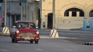 Personas con mascarillas en un coche por las calles de La Habana