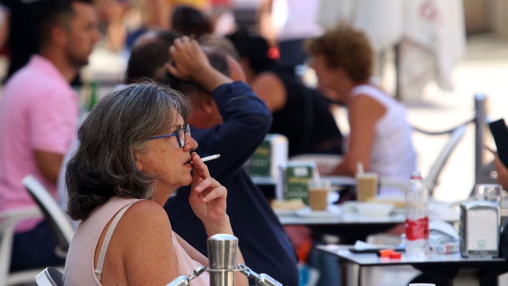 Personas fumando en terrazas y vías públicas durante el día en el que se ha decretado la prohibición de fumar en espacios públicos