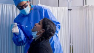 Un trabajador sanitario protegido le realiza a una mujer un test PCR en el Centro de Especialidades Carabanchel Alto.