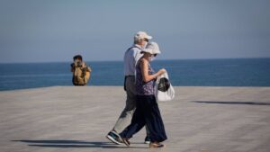 Dos personas protegidas con mascarillas pasean por el Paseo Marítimo de la Playa de la Barceloneta, en Barcelona/Catalunya