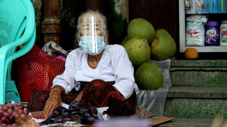 Una mujer con mascarilla en un mercado de Rangún