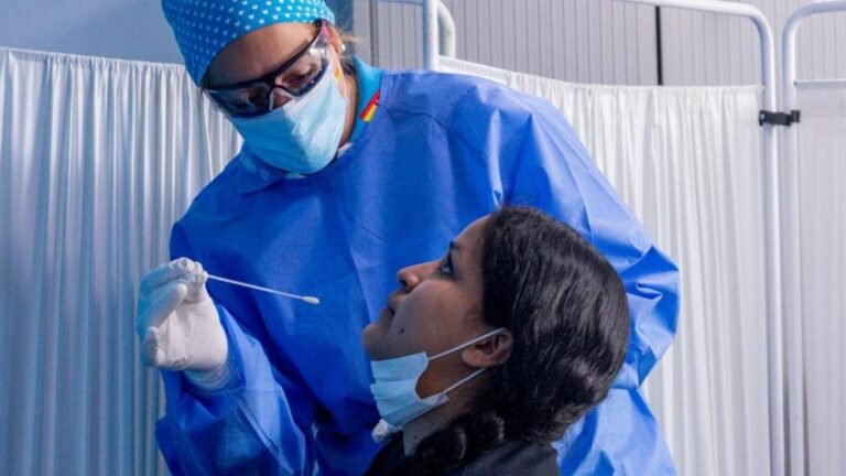 Un trabajador sanitario protegido le realiza a una mujer un test PCR en el Centro de Especialidades Carabanchel Alto.