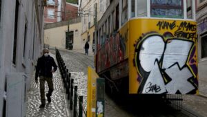 Un hombre con mascarilla junto a un tranvía de Lisboa