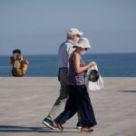 Dos personas protegidas con mascarillas pasean por el Paseo Marítimo de la Playa de la Barceloneta, en Barcelona/Catalunya