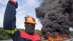 Un trabajador de Alcoa San Cibrao levanta el puño durante una manifestación en la que han cortado la Autopista A6 con la quema de neumáticos