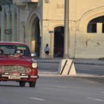Personas con mascarillas en un coche por las calles de La Habana