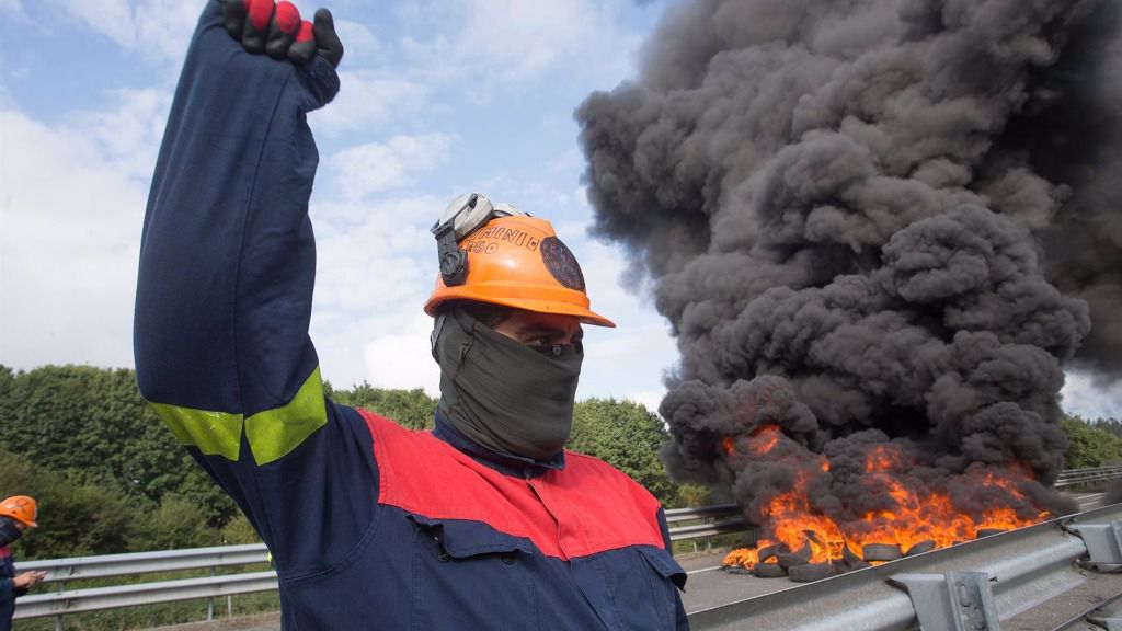 Un trabajador de Alcoa San Cibrao levanta el puño durante una manifestación en la que han cortado la Autopista A6 con la quema de neumáticos