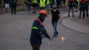 Un manifestante tira un petardo durante una concentración nocturna convocada por el comité de Alcoa San Cibrao, en el entorno de la fábrica de San Cibrao