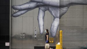 Una mujer con mascarilla paseando ante un mural en Nueva York coronavirus